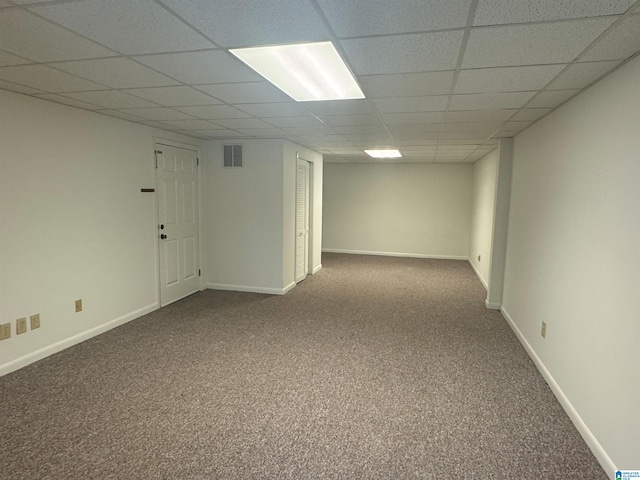 finished below grade area featuring carpet floors, a drop ceiling, visible vents, and baseboards