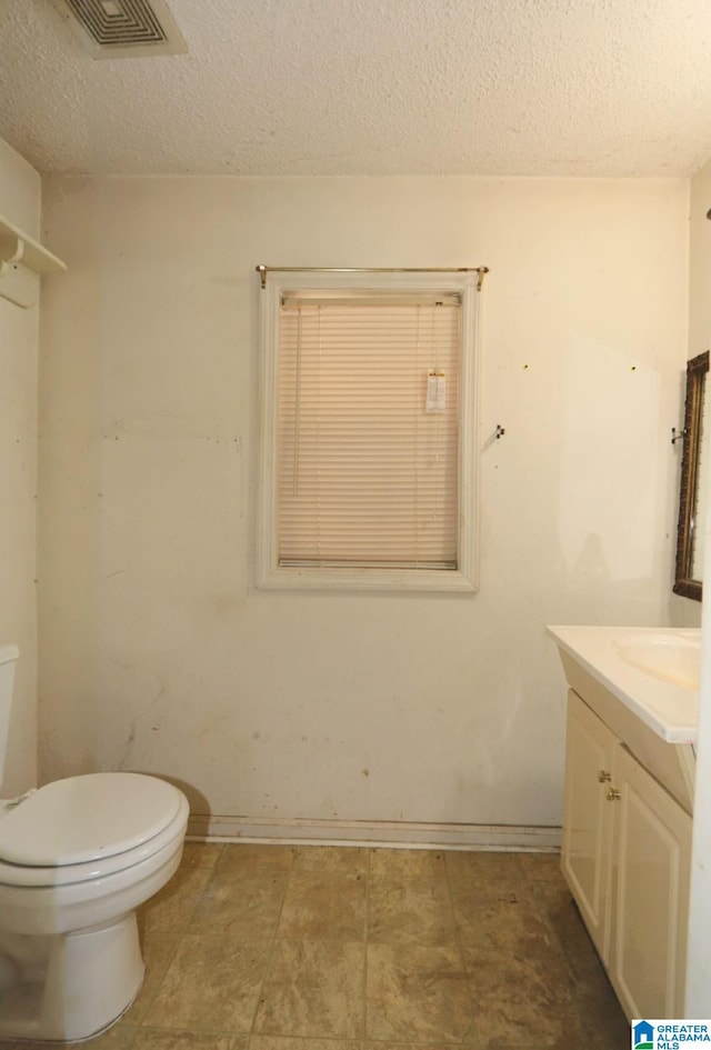 801 Walnut St, Talladega, AL 35160 - half bath with a textured ceiling, toilet, visible vents, baseboards, and vanity