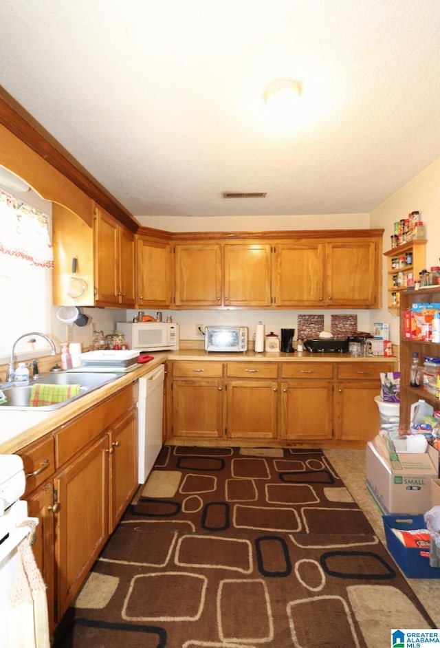 801 Walnut St, Talladega, AL 35160 - kitchen featuring light countertops, visible vents, a sink, white appliances, and brown cabinetry