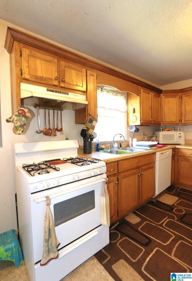 801 Walnut St, Talladega, AL 35160 - kitchen with a sink, a textured ceiling, brown cabinets, white appliances, and under cabinet range hood