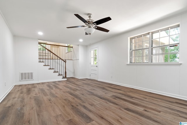 unfurnished living room featuring ceiling fan, visible vents, wood finished floors, stairway, and baseboards