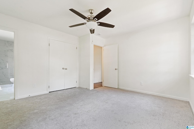 unfurnished bedroom featuring ceiling fan, carpet, baseboards, ensuite bathroom, and a closet
