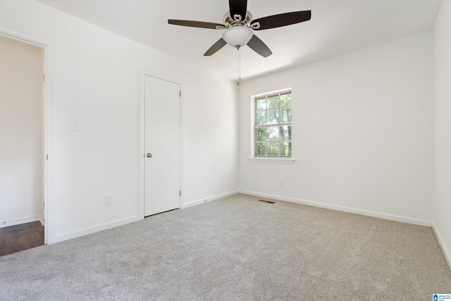 carpeted spare room with baseboards, a ceiling fan, and visible vents