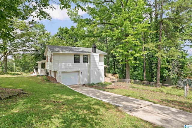 exterior space featuring a garage, fence, a chimney, concrete driveway, and a yard