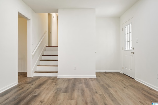 foyer with baseboards, wood finished floors, and stairway