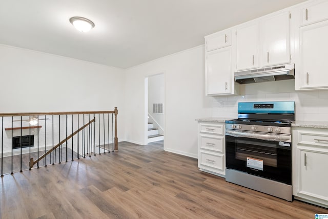 kitchen with wood finished floors, under cabinet range hood, white cabinets, backsplash, and stainless steel electric range oven