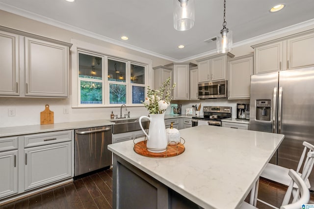 kitchen with appliances with stainless steel finishes, a kitchen bar, a sink, gray cabinetry, and pendant lighting