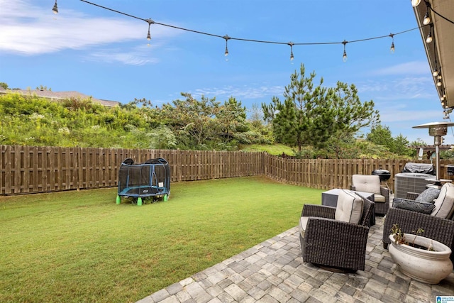 view of yard with an outdoor living space, a trampoline, a fenced backyard, and a patio area
