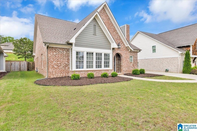 single story home with a front lawn, brick siding, a chimney, roof with shingles, and fence