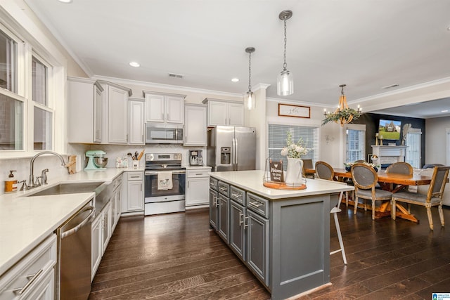 kitchen featuring crown molding, a sink, a breakfast bar, stainless steel appliances, and gray cabinets