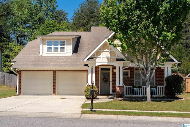 craftsman inspired home featuring concrete driveway, covered porch, fence, brick siding, and a garage