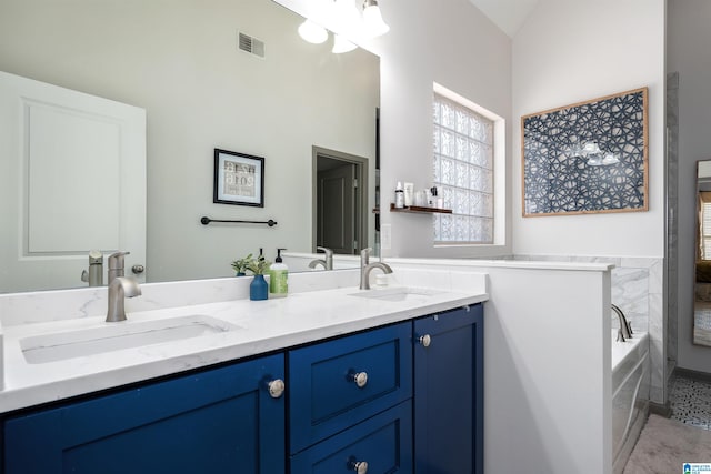 bathroom featuring a garden tub, double vanity, a sink, and visible vents
