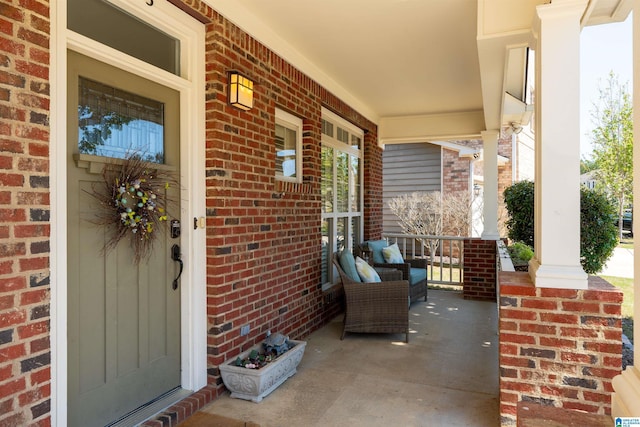 doorway to property with a porch and brick siding