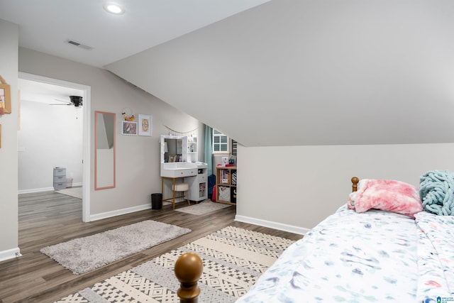 bedroom featuring visible vents, vaulted ceiling, wood finished floors, and baseboards