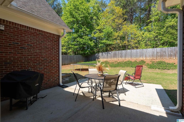 view of patio / terrace featuring grilling area, a fenced backyard, outdoor dining area, and a trampoline