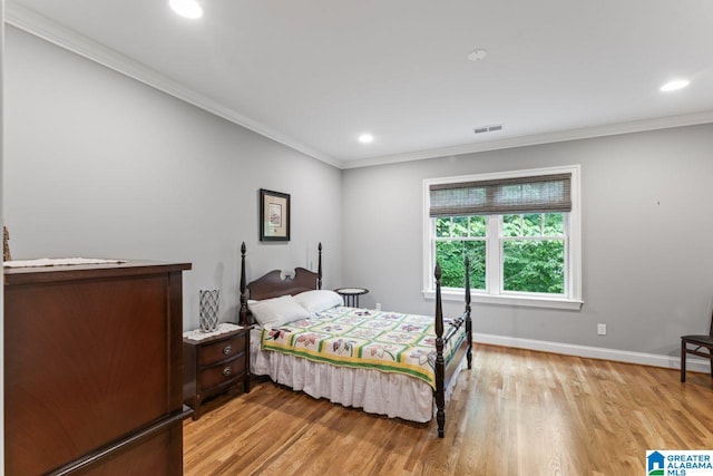 bedroom with visible vents, light wood-type flooring, ornamental molding, and baseboards