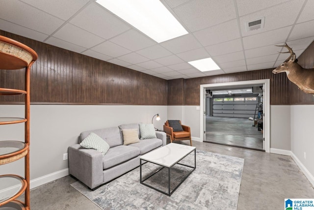 living area with baseboards, visible vents, and finished concrete floors