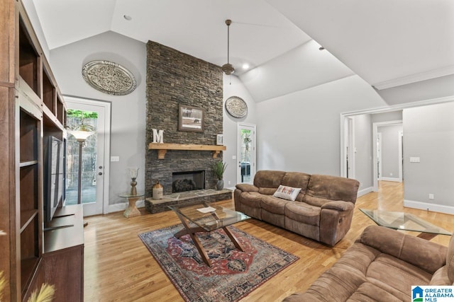 living area with baseboards, high vaulted ceiling, wood finished floors, and a stone fireplace