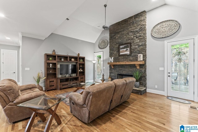 living room with high vaulted ceiling, light wood-style flooring, a stone fireplace, and baseboards