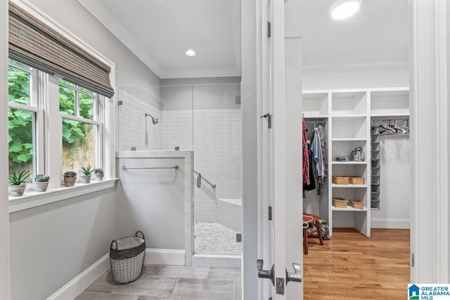 bathroom with a walk in closet, baseboards, a shower stall, and crown molding