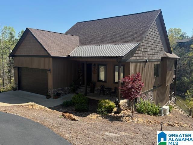 view of front of property featuring a garage, covered porch, a shingled roof, and concrete driveway