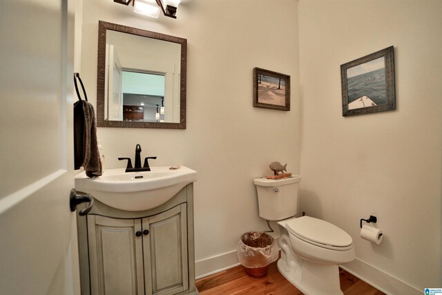 bathroom featuring wood finished floors, toilet, vanity, and baseboards