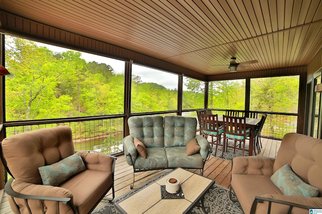 sunroom featuring an outdoor hangout area, outdoor dining area, ceiling fan, and a view of trees