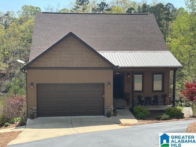 view of front of property with concrete driveway, a porch, an attached garage, and stone siding