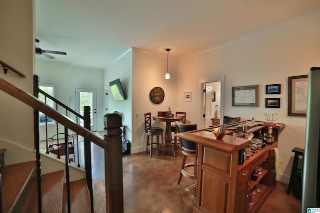 interior space with concrete floors, ceiling fan, baseboards, ornamental molding, and stairs