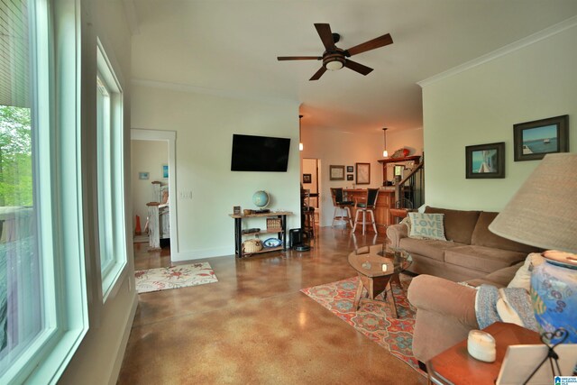 living room featuring crown molding, a ceiling fan, finished concrete flooring, and baseboards