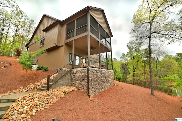 view of side of home with ceiling fan and stairway