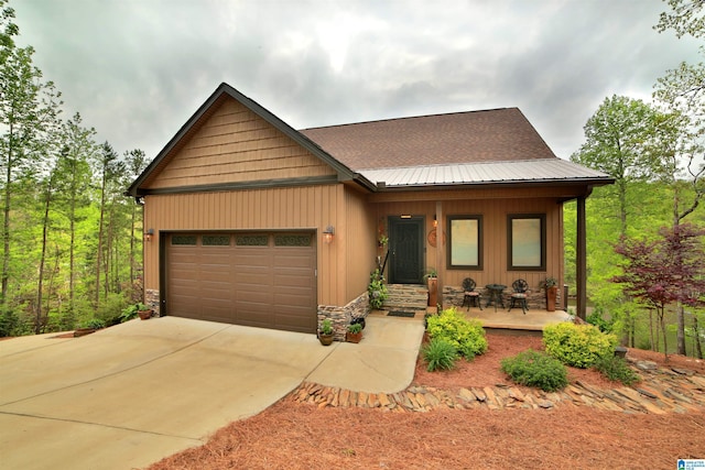 view of front of property featuring concrete driveway, a garage, and covered porch
