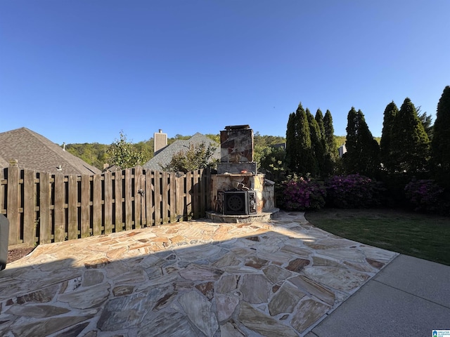 view of patio with fence, an outdoor stone fireplace, and ac unit