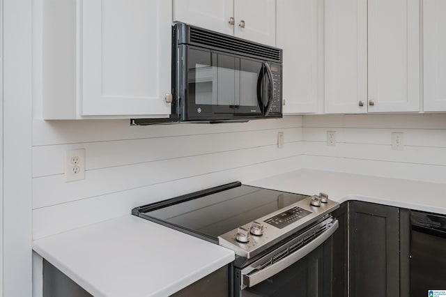 kitchen with stainless steel electric stove, light countertops, black microwave, and white cabinets