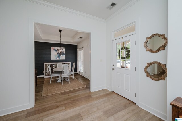entryway featuring a notable chandelier, light wood-style flooring, baseboards, ornamental molding, and visible vents