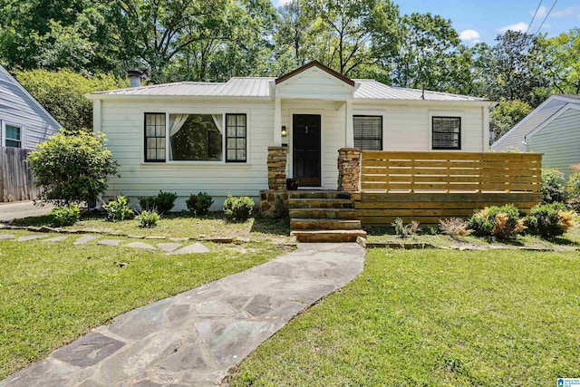 view of front facade with fence, metal roof, and a front lawn