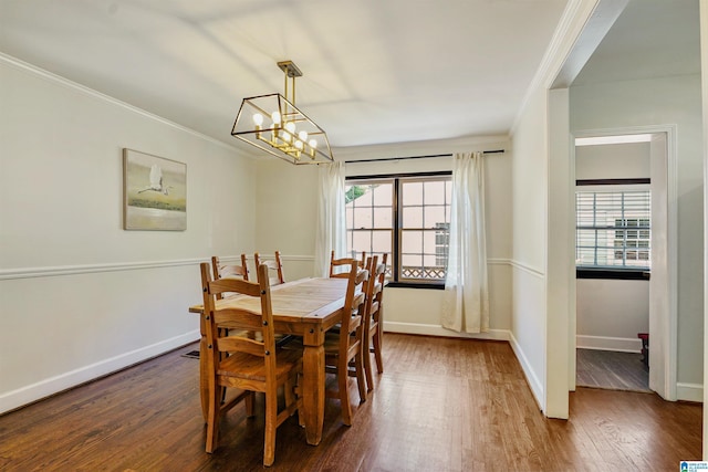 dining area with dark wood-type flooring, ornamental molding, baseboards, and a notable chandelier