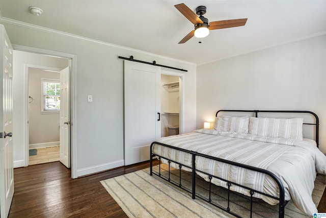 bedroom with ornamental molding, a barn door, and wood finished floors