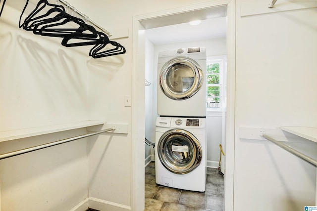 clothes washing area featuring stacked washing maching and dryer, baseboards, and laundry area
