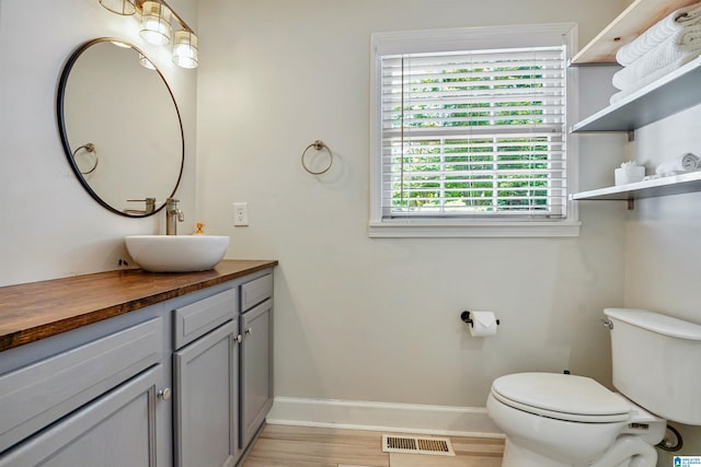 bathroom featuring visible vents, wood finished floors, baseboards, vanity, and toilet