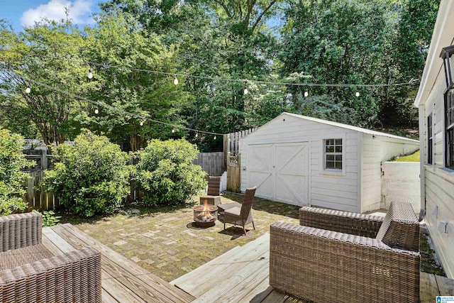 wooden deck with an outdoor structure, a fenced backyard, an outdoor fire pit, and a shed