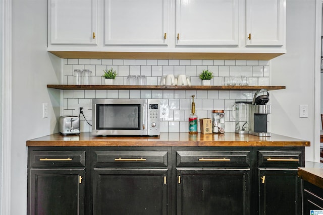 bar featuring decorative backsplash and stainless steel microwave