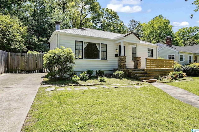 view of front of property featuring fence, driveway, metal roof, and a front yard