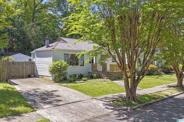 view of front of property featuring fence, a front lawn, driveway, and metal roof