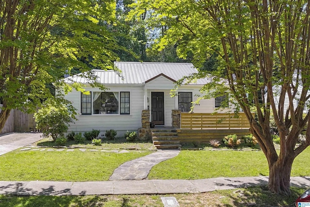 bungalow-style house with fence, metal roof, and a front lawn