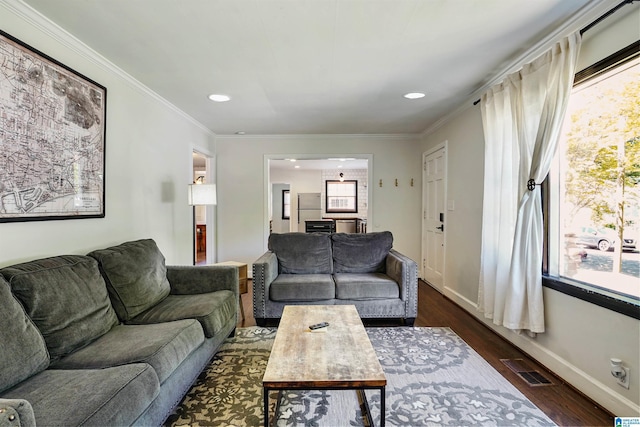 living room with dark wood-type flooring, ornamental molding, a healthy amount of sunlight, and visible vents