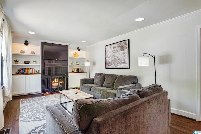living area with crown molding, a brick fireplace, dark wood finished floors, recessed lighting, and visible vents