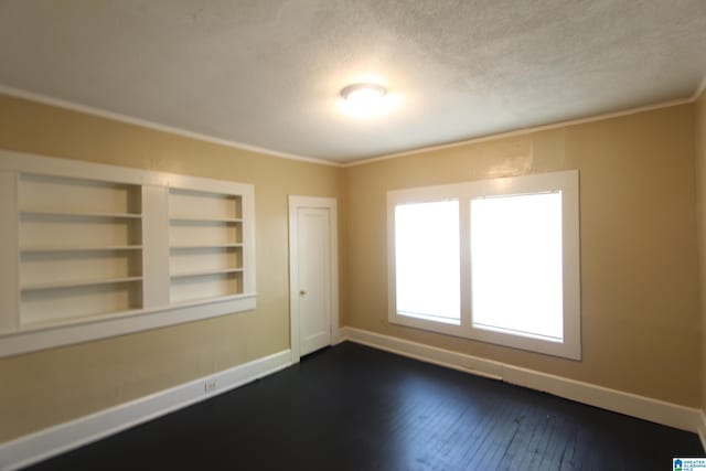 empty room featuring dark wood finished floors, baseboards, crown molding, and a textured ceiling