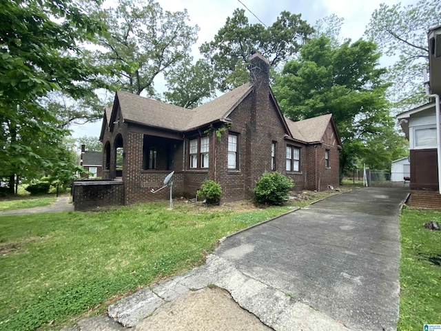 view of property exterior featuring brick siding, a yard, driveway, and a chimney