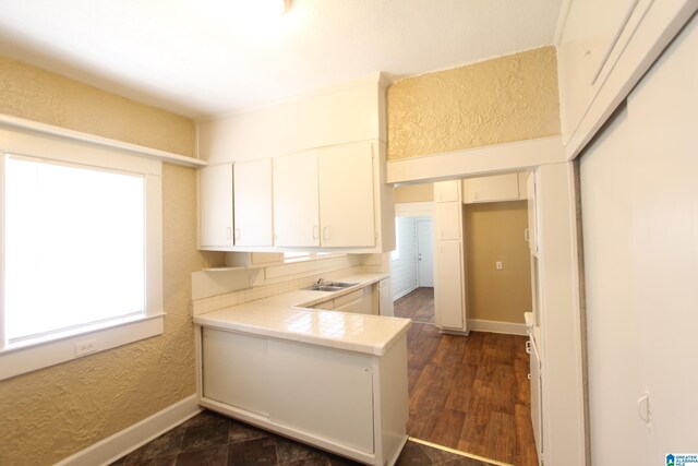 kitchen with baseboards, a healthy amount of sunlight, a textured wall, and white cabinetry